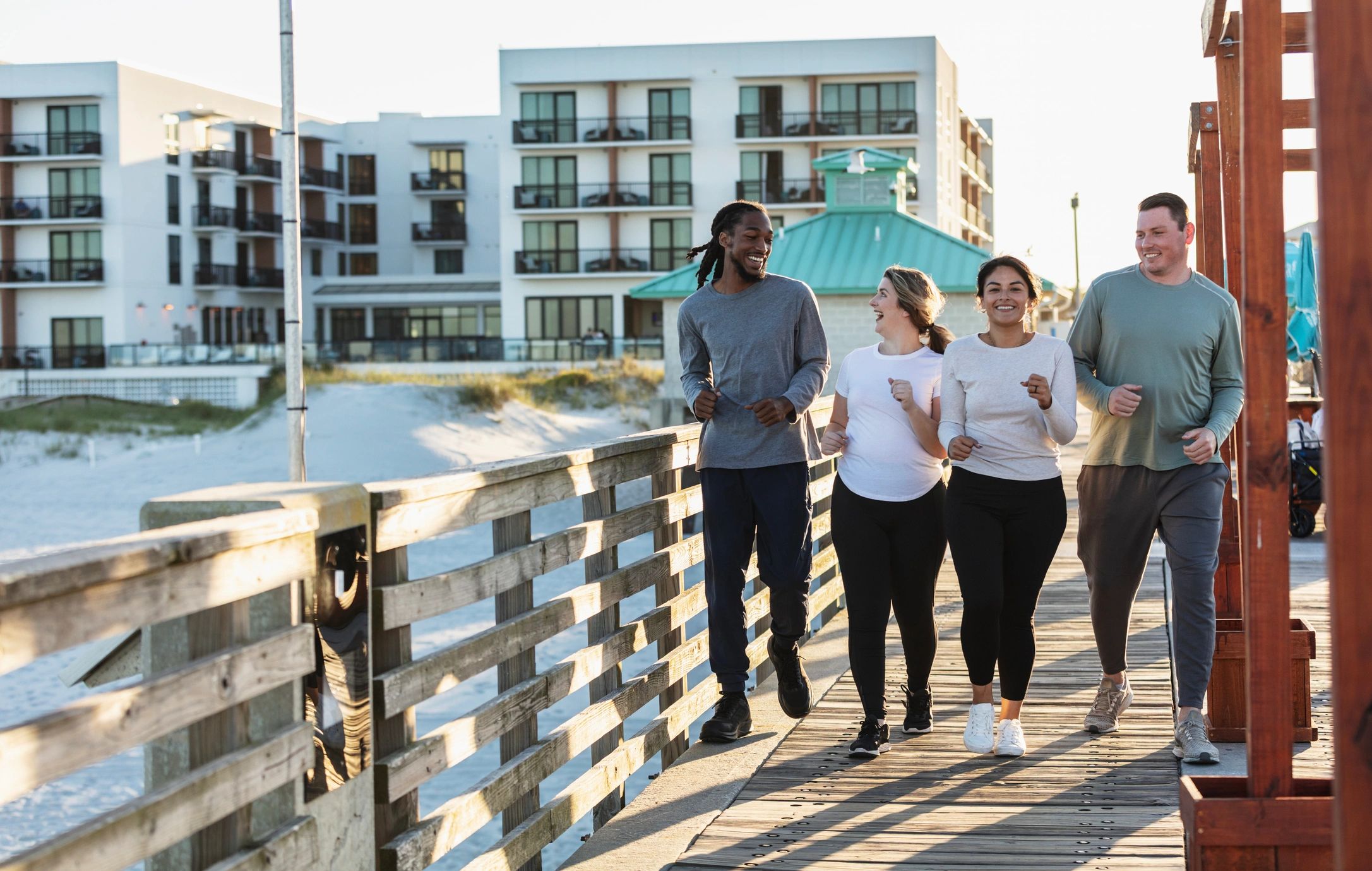 Multiracial group of friends running on beach boardwalk