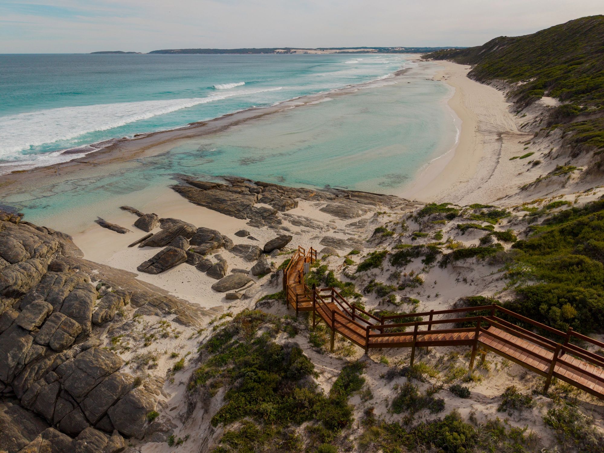 Boardwalk stairs leading down to a bright sandy beach